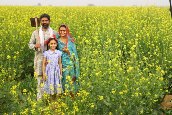 Indian happy rural family in village with mustard field